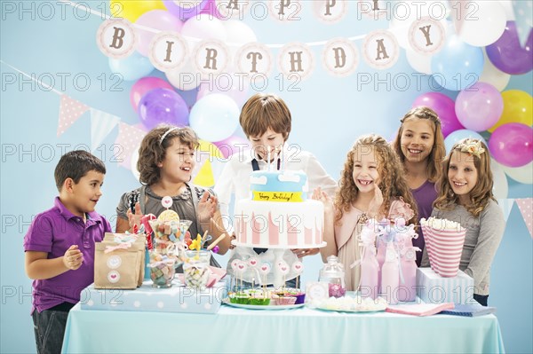 Children smiling near cake and gifts at birthday party