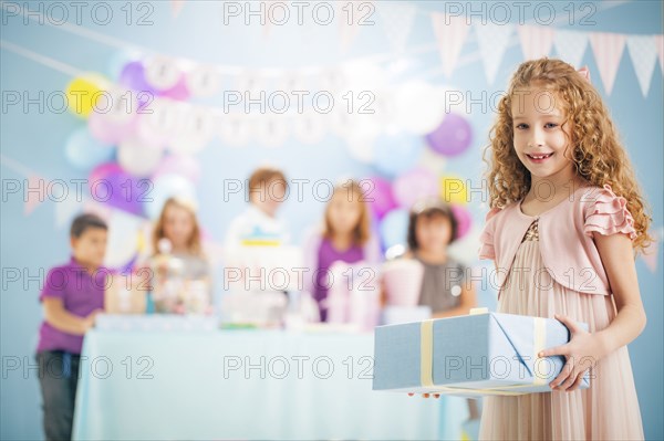 Girl holding wrapped gift at birthday party