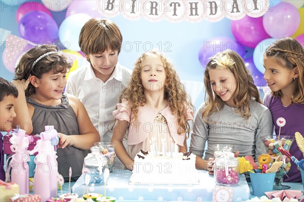 Girl wishing over birthday cake at party