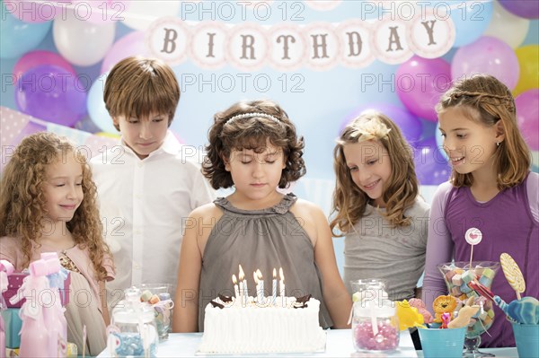 Girl wishing over birthday cake at party