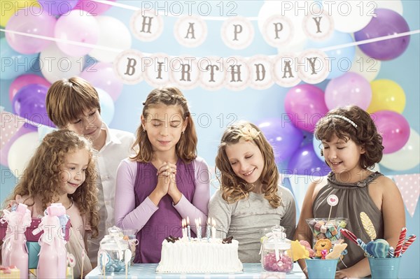 Girl wishing over birthday cake at party