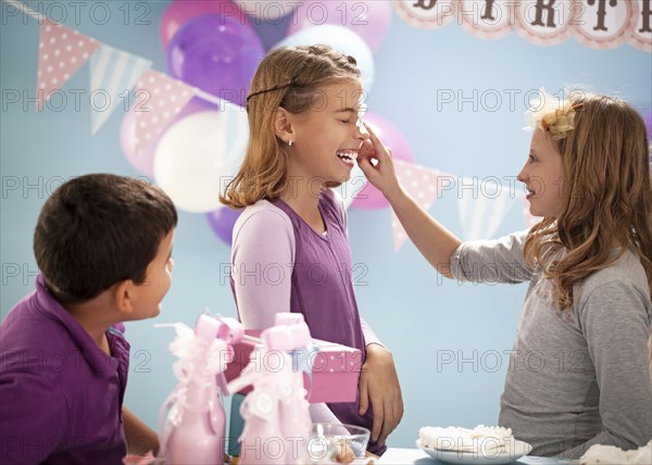 Girls playing with birthday cake at party