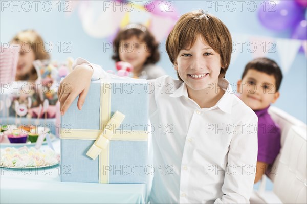 Boy smiling with wrapped gift at birthday party