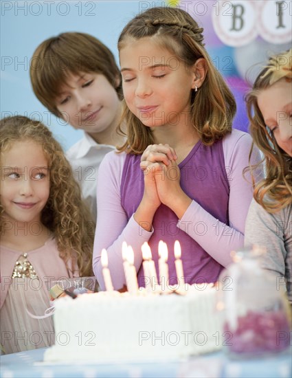 Girl wishing over birthday cake at party