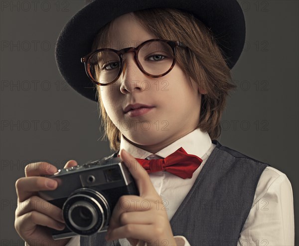 Close up of boy in hat photographing with vintage camera