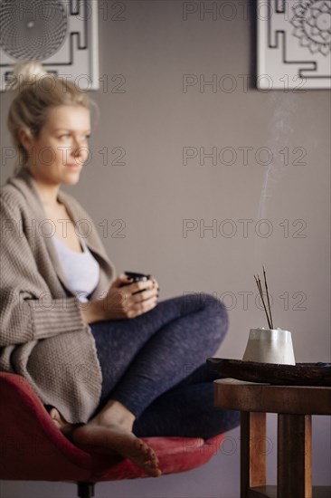 Caucasian woman burning incense in living room