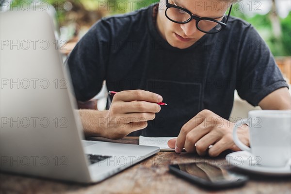 Caucasian man writing in cafe