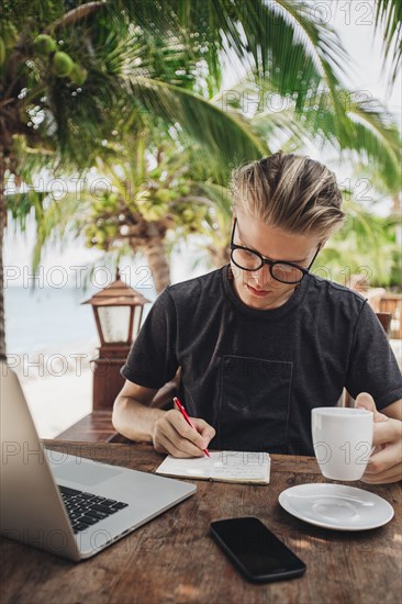 Caucasian man writing in cafe