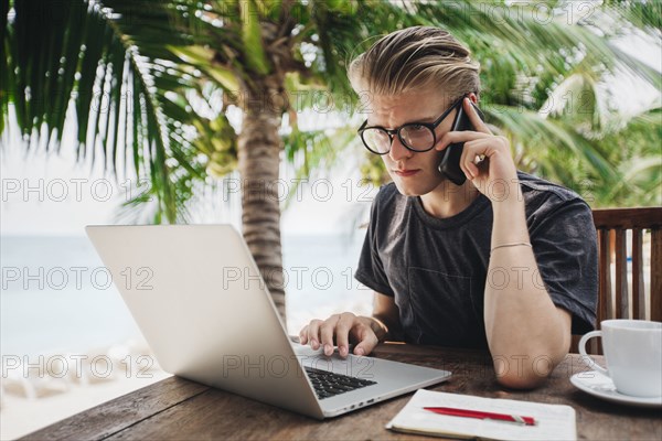 Caucasian man talking on cell phone in cafe