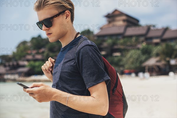 Caucasian man using cell phone on beach