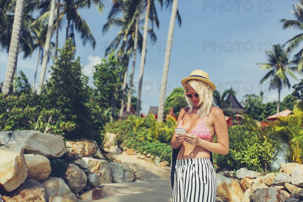 Caucasian woman using cell phone on beach