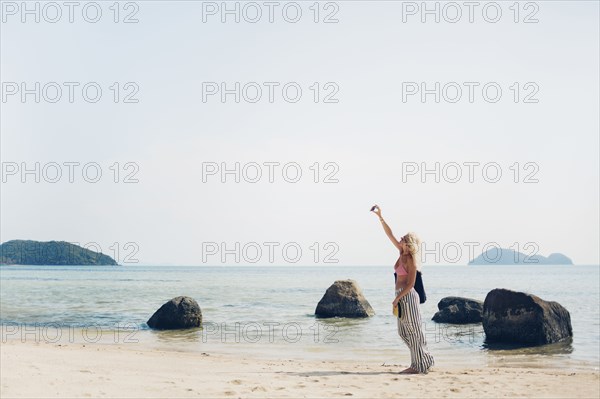 Caucasian woman taking selfie on beach