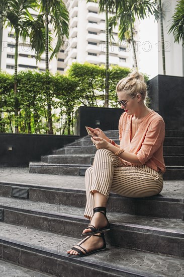 Caucasian woman using cell phone on stairs