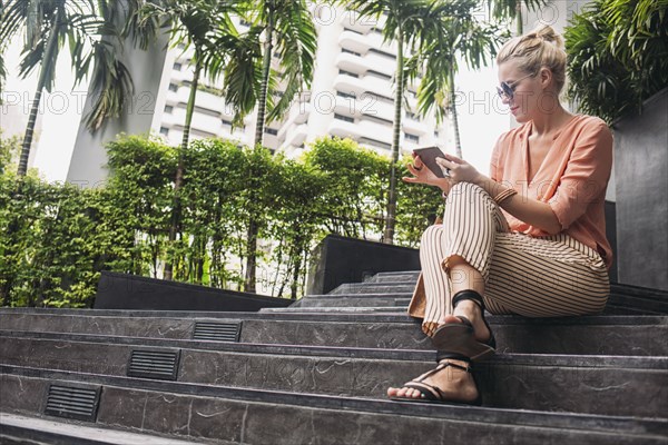 Caucasian woman using cell phone on stairs