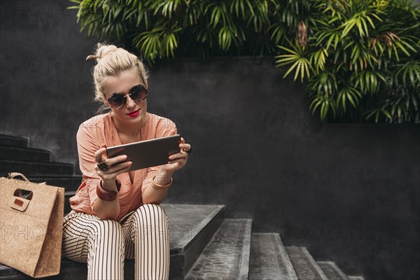 Caucasian woman using digital tablet on stairs