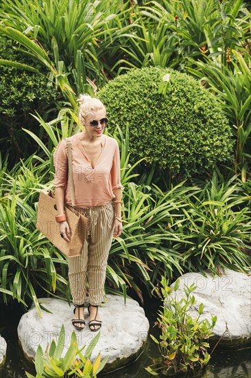 Caucasian woman standing on stone in pond