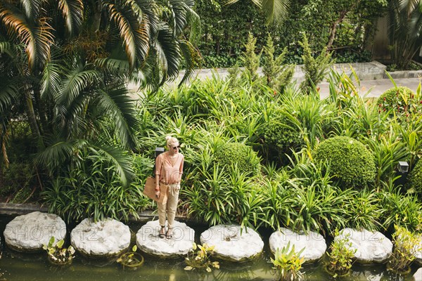 Caucasian woman standing on stone in pond