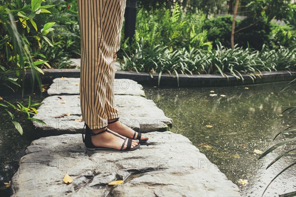 Caucasian woman standing on stone in pond