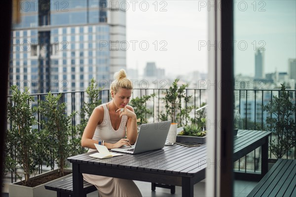 Caucasian woman using laptop on balcony