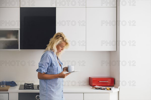 Woman using digital tablet in kitchen