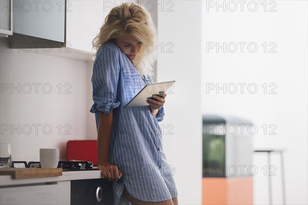 Woman using digital tablet in kitchen