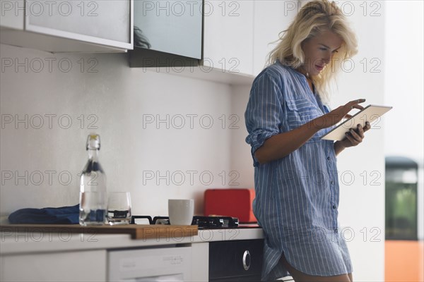 Woman using digital tablet in kitchen