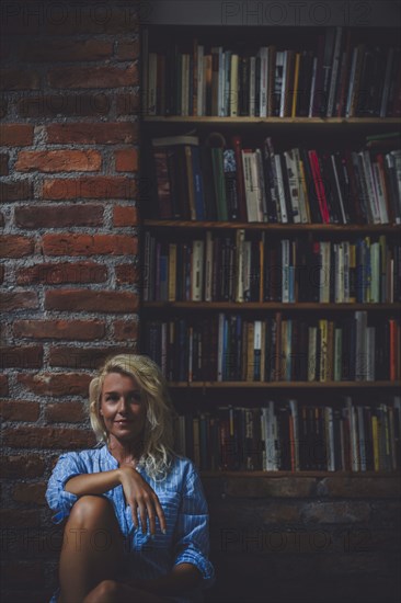 Smiling woman sitting near bookcase