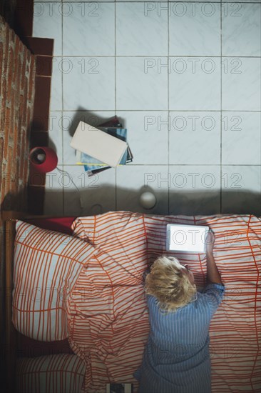 Woman using digital tablet on bed