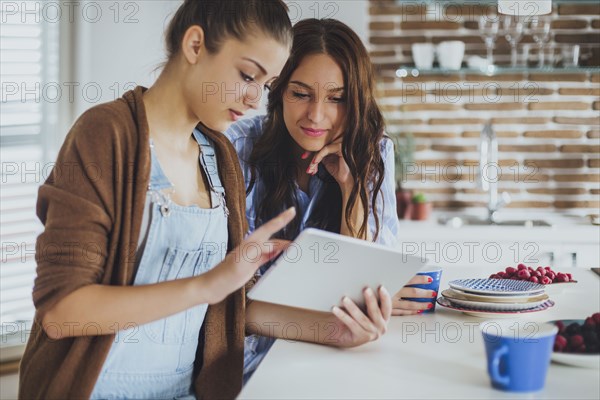 Caucasian women using digital tablet in kitchen