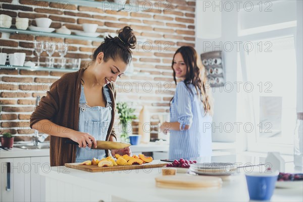 Caucasian women chopping fruit in kitchen