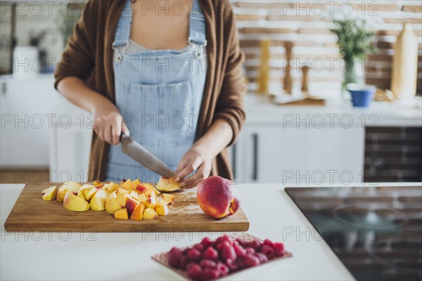 Caucasian woman chopping fruit in kitchen