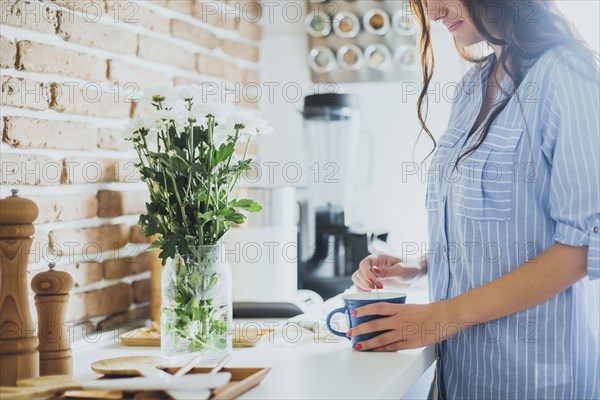 Caucasian woman stirring coffee in kitchen