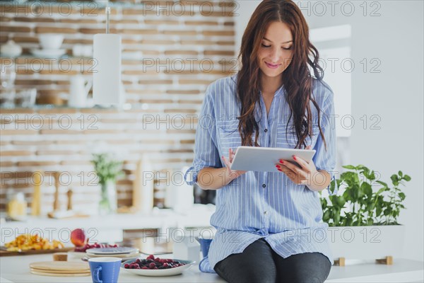 Caucasian woman using digital tablet in kitchen