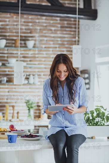 Caucasian woman using digital tablet in kitchen