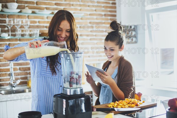 Caucasian women making smoothie in kitchen