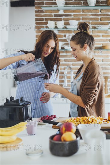 Caucasian women pouring smoothie in kitchen