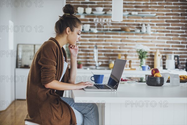 Caucasian woman using laptop in kitchen