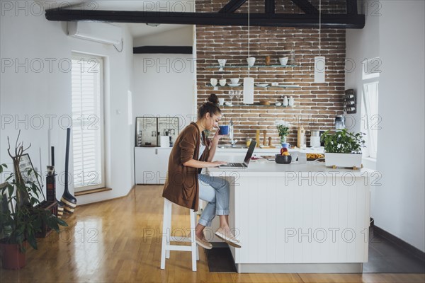 Caucasian woman using laptop in kitchen