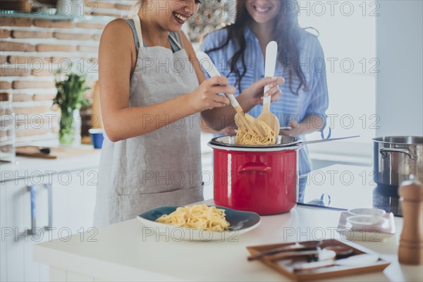 Caucasian women cooking pasta in kitchen