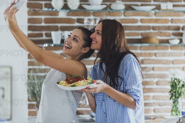 Caucasian women taking selfie in kitchen with pasta