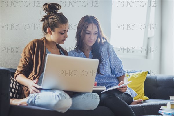 Caucasian women using laptop on sofa