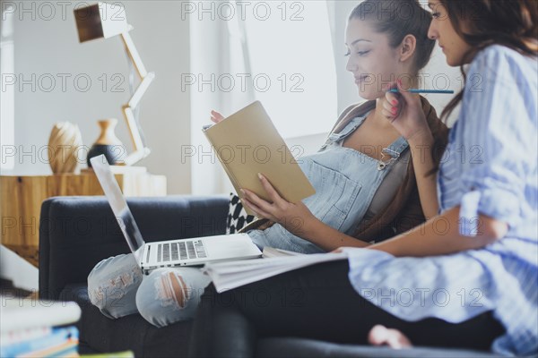 Caucasian women studying on sofa