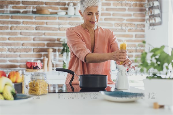 Older Caucasian woman cooking spaghetti in kitchen