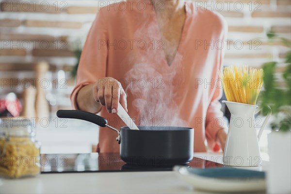 Older Caucasian woman cooking in kitchen