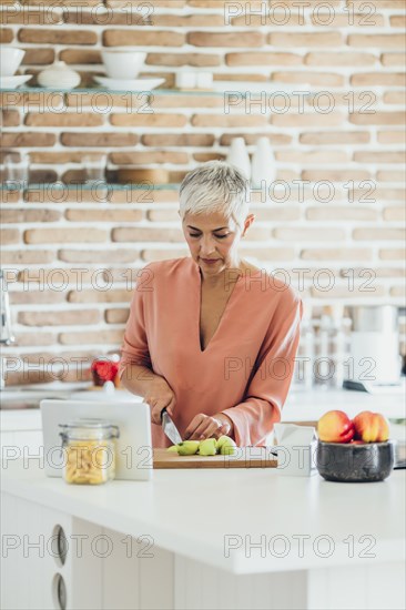 Older Caucasian woman cutting apples in kitchen