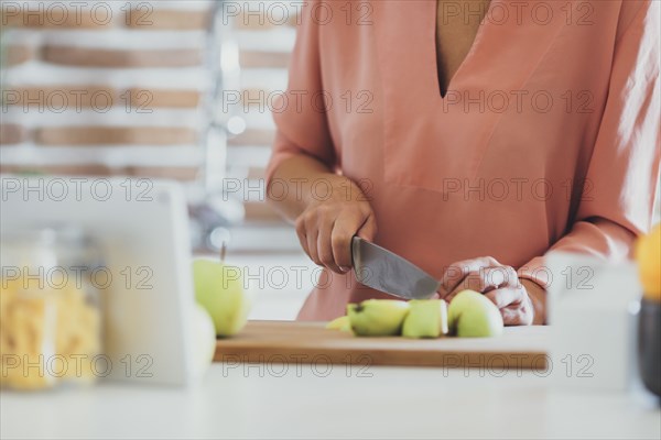 Older Caucasian woman cutting apples in kitchen