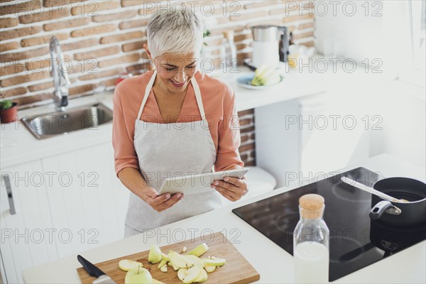 Older Caucasian woman using digital tablet in kitchen