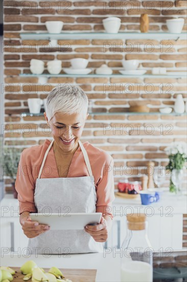 Older Caucasian woman using digital tablet in kitchen