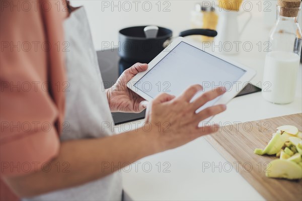 Older Caucasian woman using digital tablet in kitchen