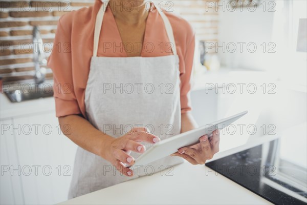 Older Caucasian woman using digital tablet in kitchen